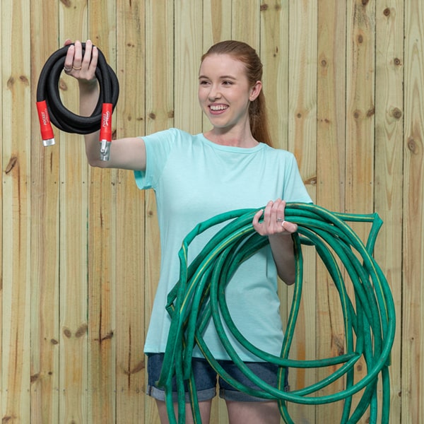 Silver Bullet being held up easily by a woman to show light weight and compactness contrasted with large, heavy, dirty rubber hose in other arm