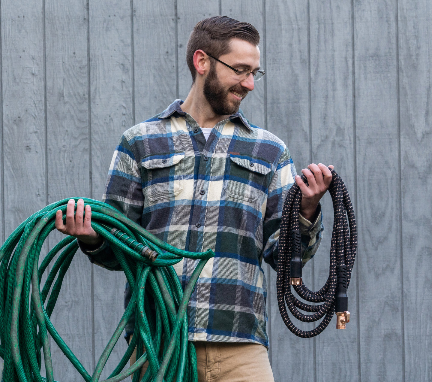 Man with cumbersome rubber hose in one arm and the compact Copper Bullet hose in the other